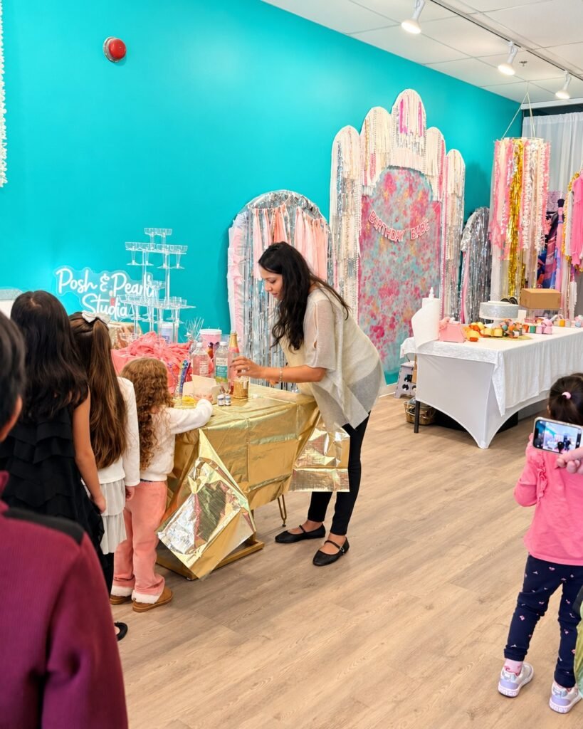 A studio team member helping children create art at Posh & Pearl Studio